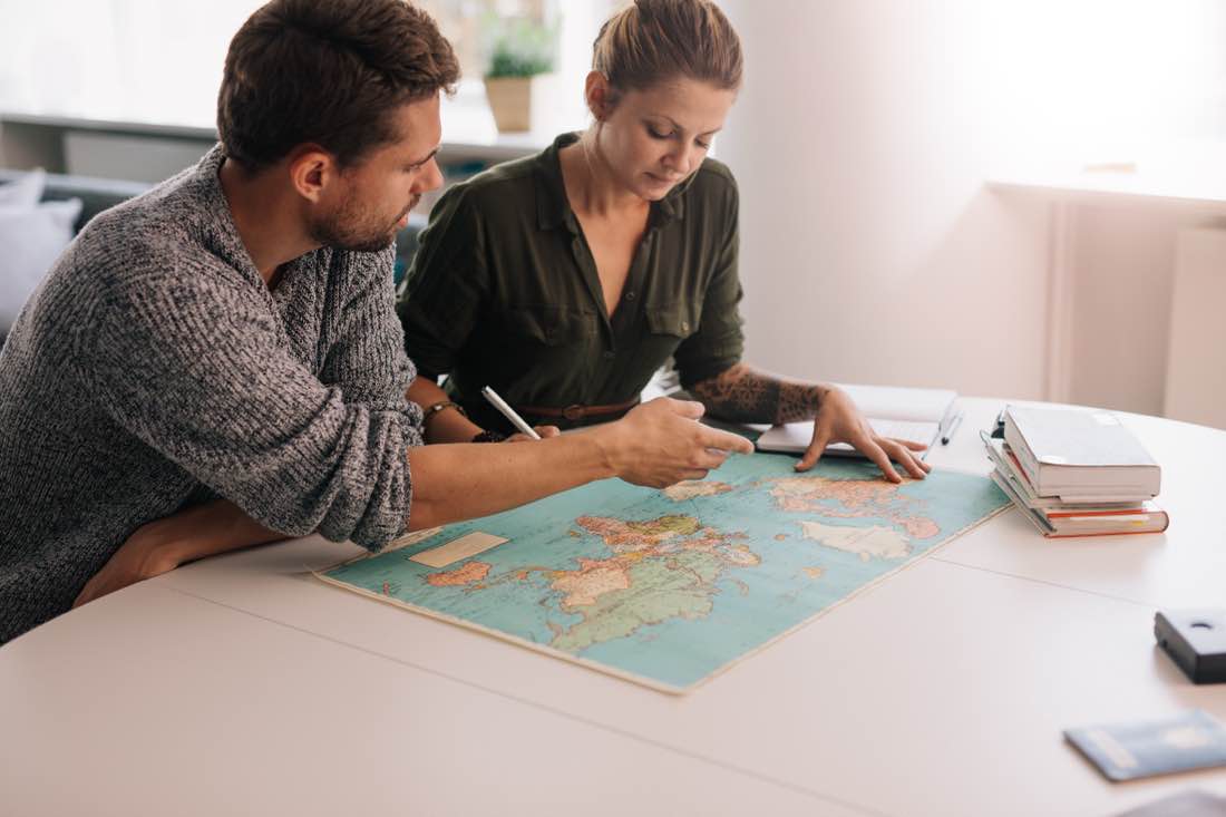 Couple reviewing a world map while considering Australian CGT changes 2027 and overseas relocation